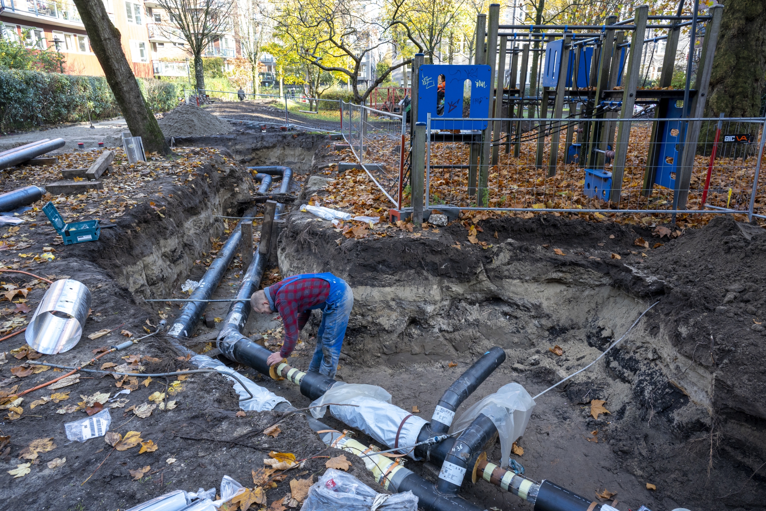 Een medewerker van Van der Lubbe Kabel- en Leidingwerken BV werkt aan de aansluiting van de ondergrondse leidingdelen van het warmtenet van KetelhuisWG, de energiecoöperatie van het WG-terrein in Amsterdam Oud-West. Foto: ANP/Hollandse Hoogte/Co de Kruijf.