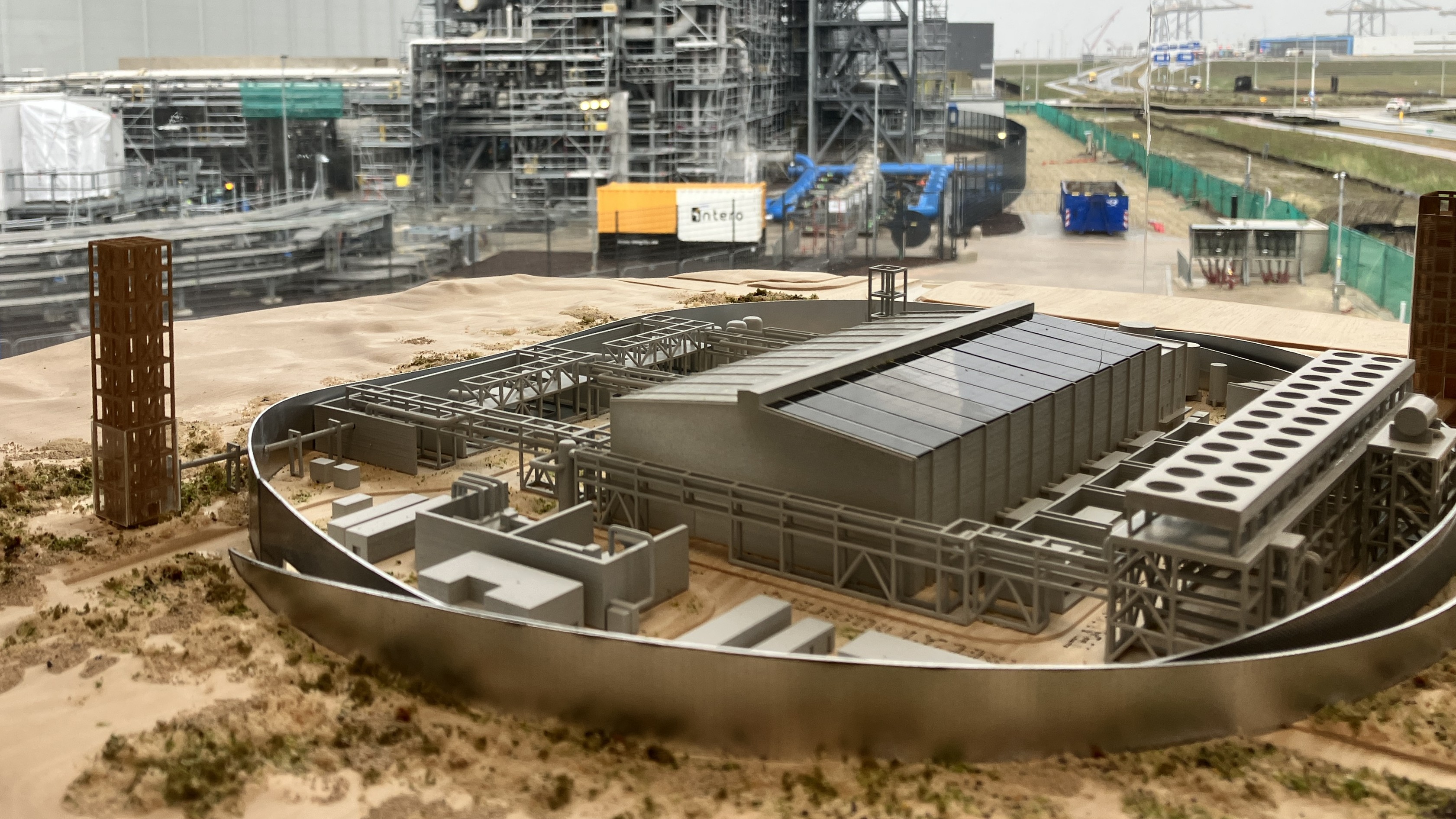 Een maquette van de Holland Hydrogen I, met de échte elektrolyser in aanbouw op de achtergrond. Foto: Tijdo van der Zee