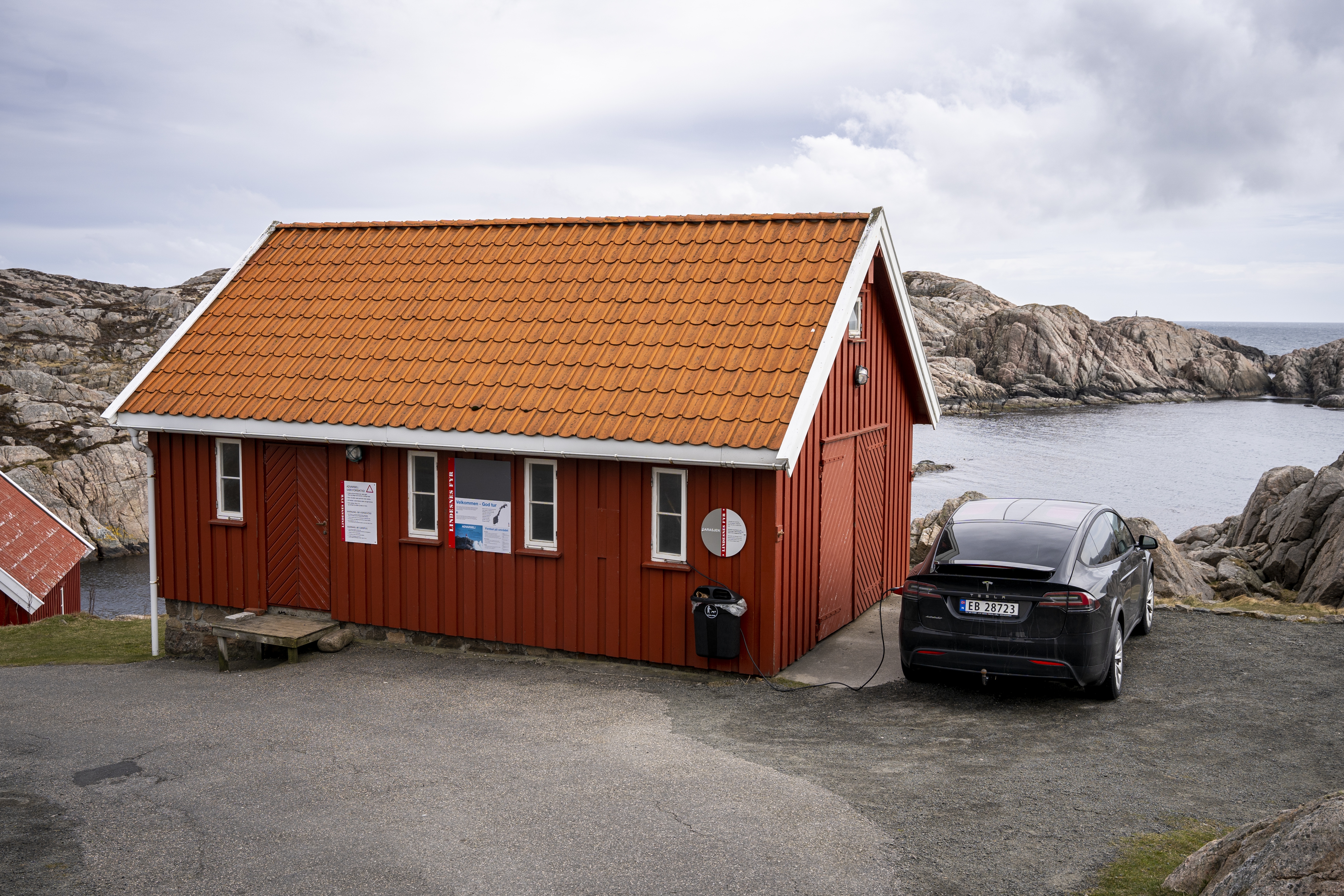 Een Tesla Model Y wordt opgeladen naast een gebouw nabij de Lindesnes Fyr, een vuurtoren in het zuiden van Noorwegen. Foto: ANP/Hollandse Hoogte/Tobias Kleuver